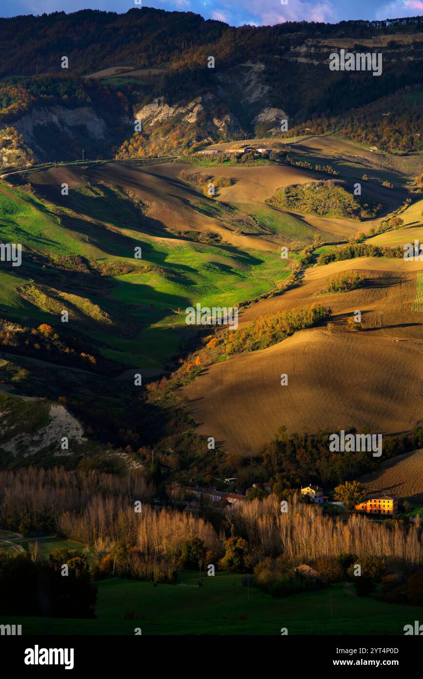 Panorama di campi e colline del Montefeltro in autunno nell'ora d'oro contro il cielo nuvoloso Foto Stock