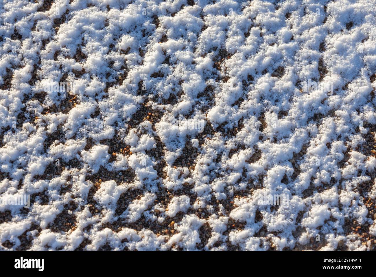 Terreno ghiacciato, sabbia ricoperta di neve su una spiaggia. Costa del Mar Baltico in una soleggiata giornata invernale. Foto di sfondo naturale astratta Foto Stock