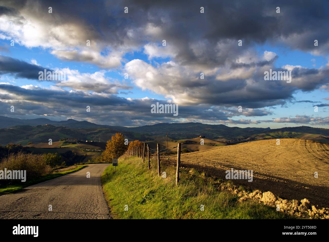 Panorama di campi e colline del Montefeltro in autunno nell'ora d'oro contro il cielo nuvoloso Foto Stock