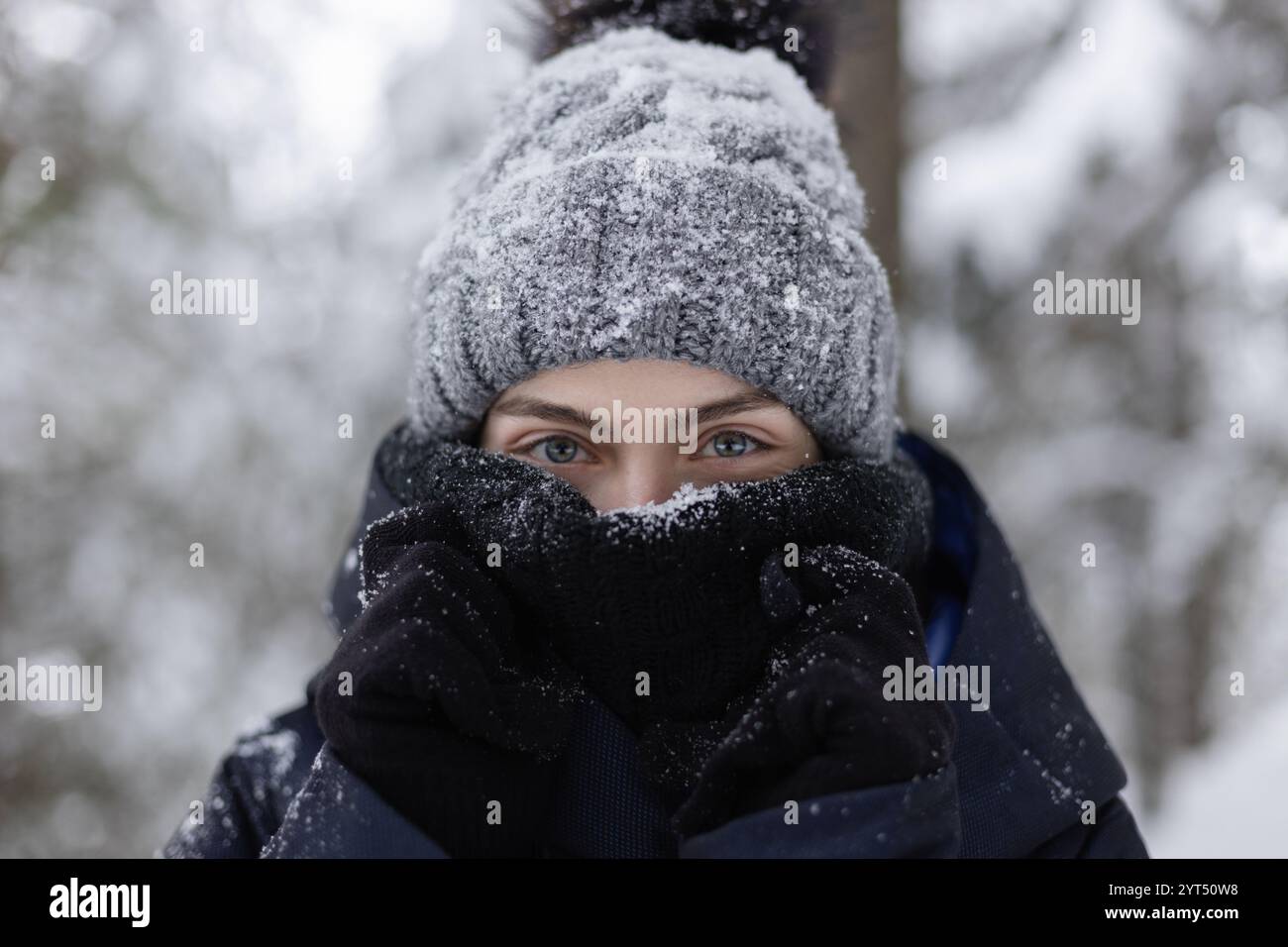 Primo piano di una giovane donna con sciarpa e cappello ricoperto di neve Foto Stock