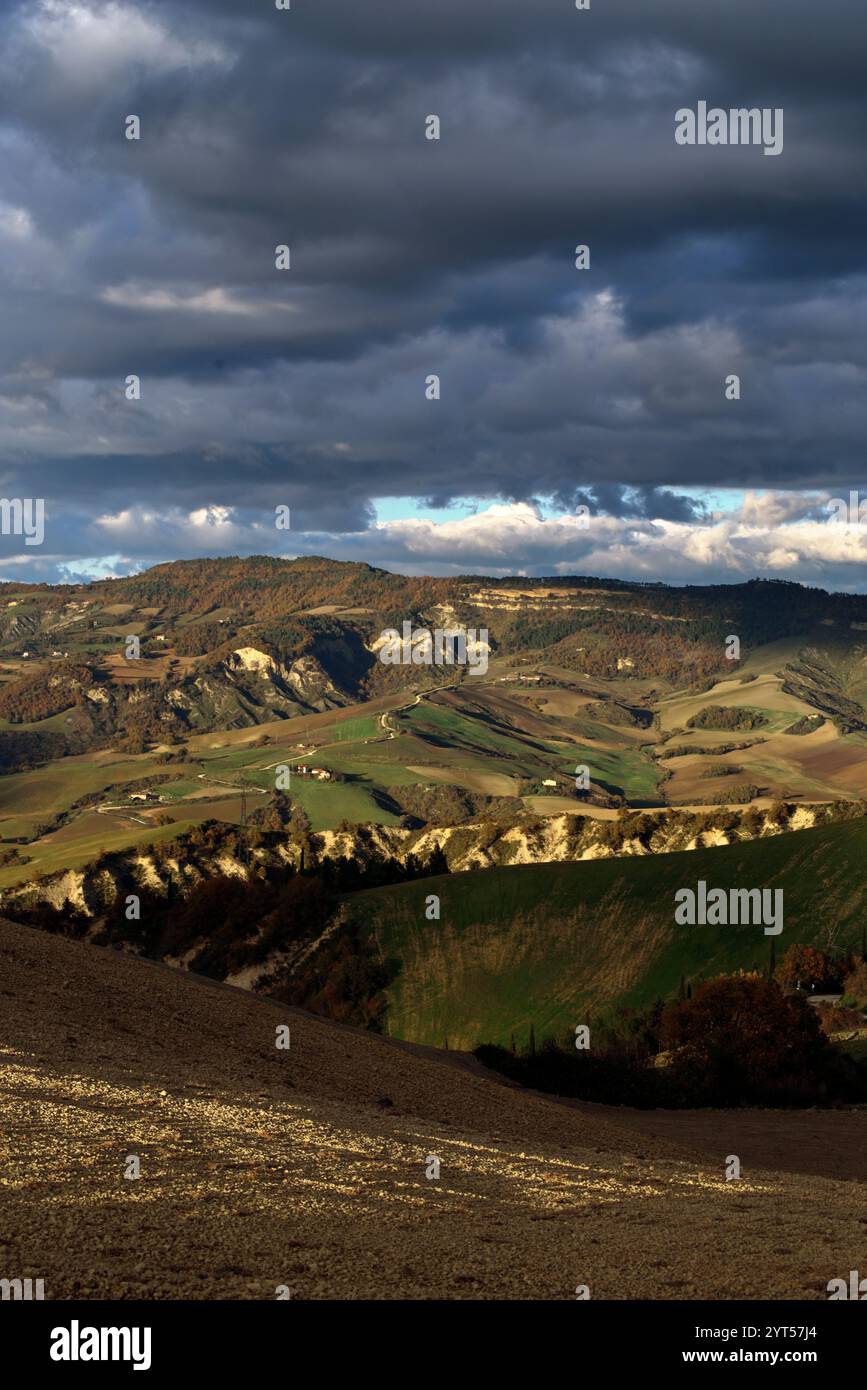 Panorama di campi e colline del Montefeltro in autunno nell'ora d'oro contro il cielo nuvoloso Foto Stock