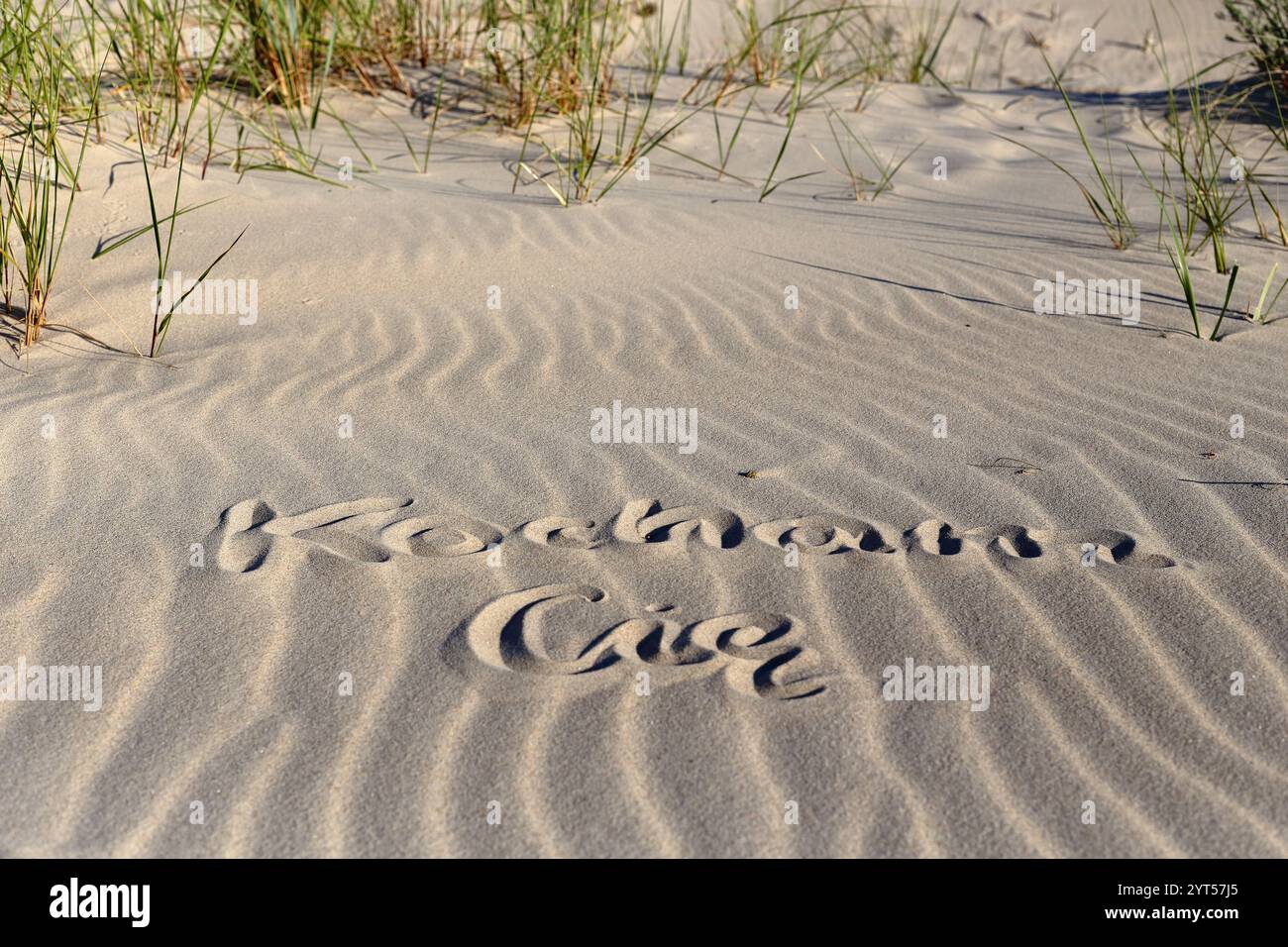 Un romantico messaggio di "Kocham Cię" (ti amo in polacco) scritto sulla sabbia su una bellissima spiaggia, con le onde dell'oceano che si infrangono dolcemente sullo sfondo. Foto Stock