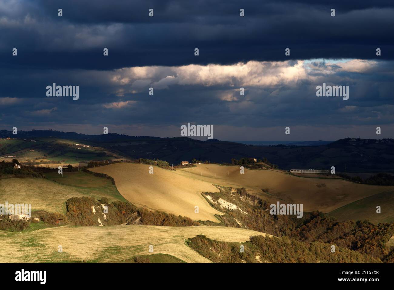 Panorama di campi e colline del Montefeltro in autunno nell'ora d'oro contro il cielo nuvoloso Foto Stock