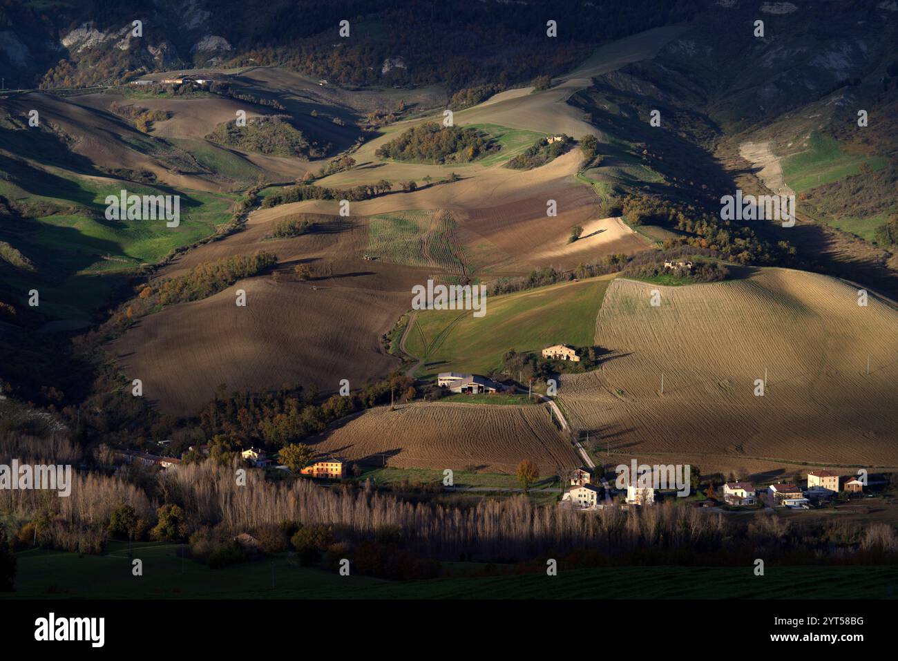 Panorama di campi e colline del Montefeltro in autunno nell'ora d'oro contro il cielo nuvoloso Foto Stock