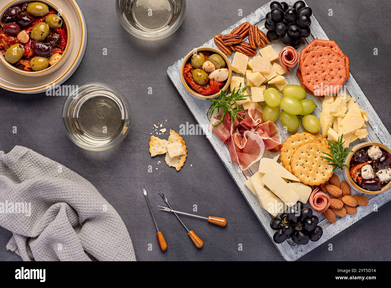 Fotografia gastronomica di vino bianco e antipasto con parmigiano, formaggio di pecora, cheddar maturo, prosciutto di serrano, uva, pecan; mandorla, cracker Foto Stock