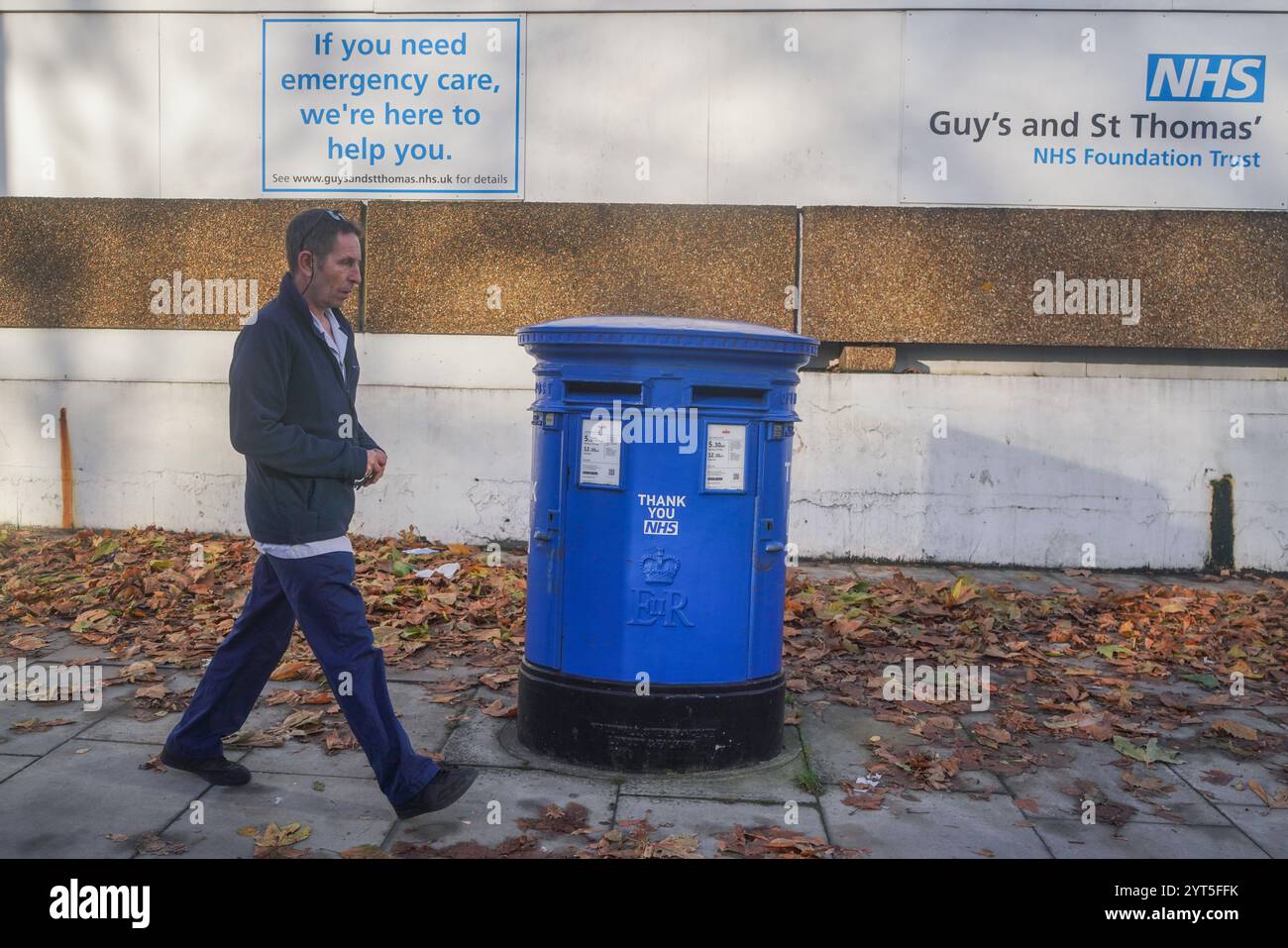 Londra, Regno Unito. 6 dicembre 2024 Un pedone passa davanti a una cassetta postale dipinta in blu come ringraziamento al NHS fuori dall'ospedale St Thomas a Westminster. Il servizio sanitario nazionale sta affrontando un quad-demic sanitario quest'inverno, poiché il numero di persone ricoverate in ospedale con influenza è aumentato del 350%, esercitando una pressione significativa sul servizio sanitario nazionale a causa dell'aumento dei casi di influenza e covid rispetto al credito dello scorso anno. Amer Ghazzal/Alamy Live News Foto Stock