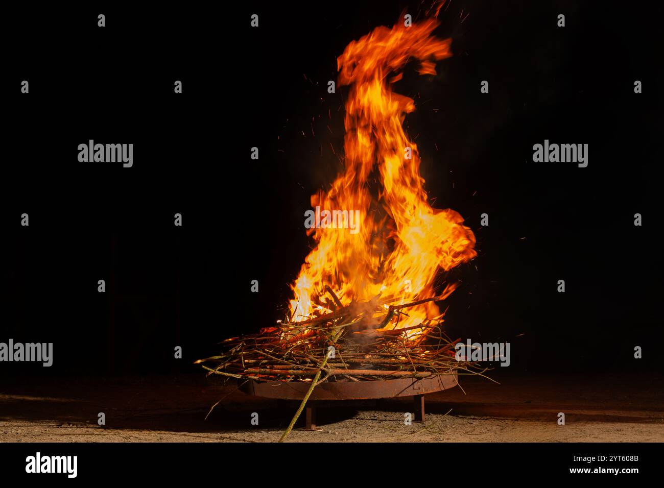 Falò con fiamme luminose contro il cielo scuro Foto Stock