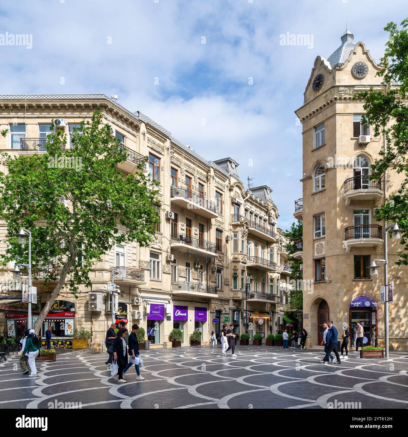 Baku, Azerbaigian - 5 maggio 2024: I visitatori passeggiano piacevolmente lungo via Nizami a Baku, Azerbaigian, circondati da affascinanti negozi e alberi lussureggianti sotto un cielo nuvoloso, creando un'atmosfera urbana vivace Foto Stock
