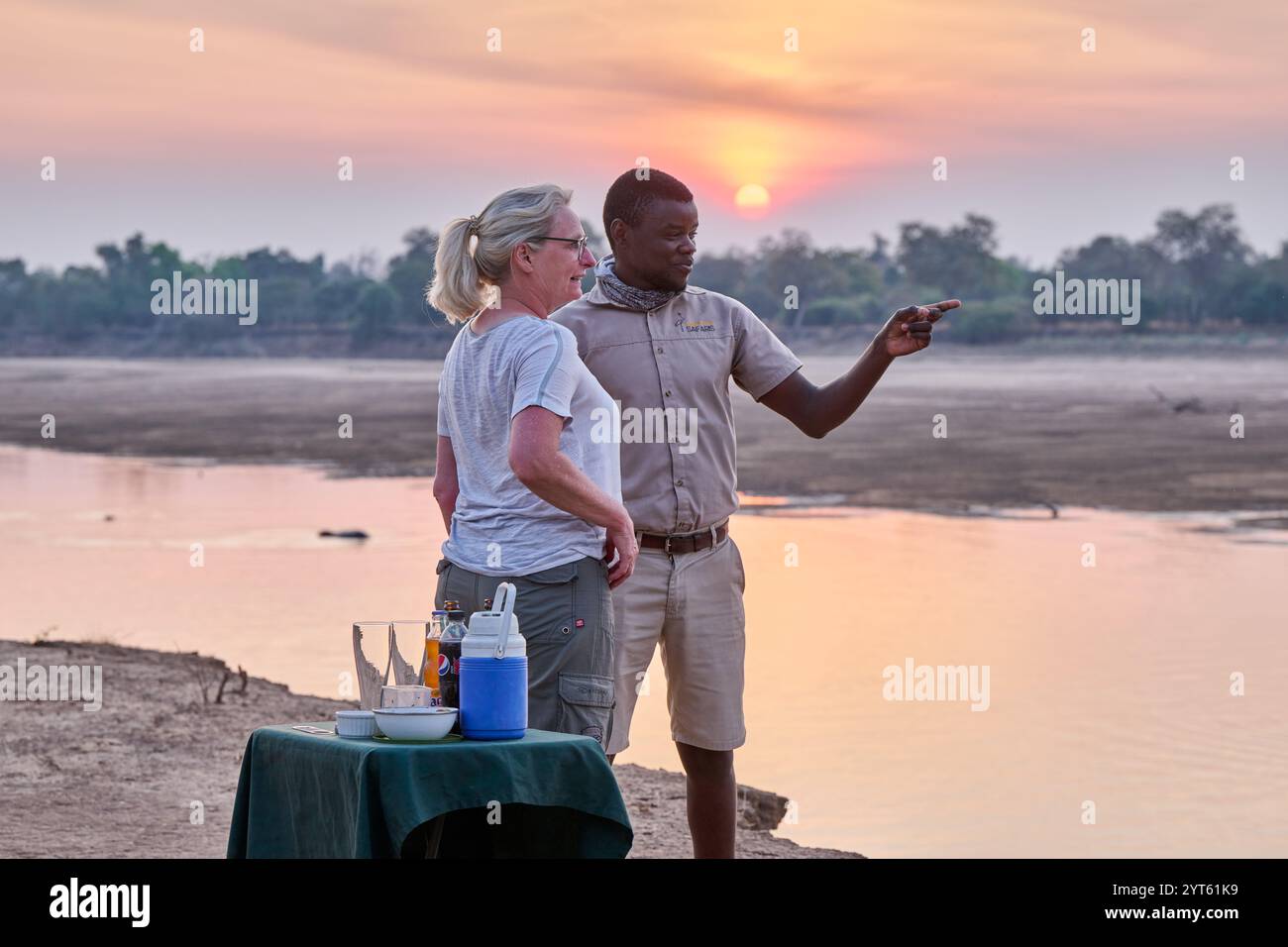 Turista e guida che prende il sole al fiume Luangwa, al Parco Nazionale Luangwa Sud, Mfuwe, Zambia, Africa Foto Stock
