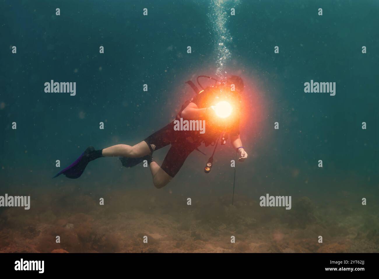Scopri le profondità torbide con una torcia luminosa, navigando attraverso l'ambiente sottomarino durante un'impegnativa immersione in acqua fangosa Foto Stock