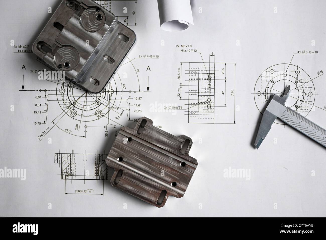 Parti metalliche lavorate su un disegno tecnico con un calibro, che mostra l'ingegneria e la produzione di precisione. Foto Stock