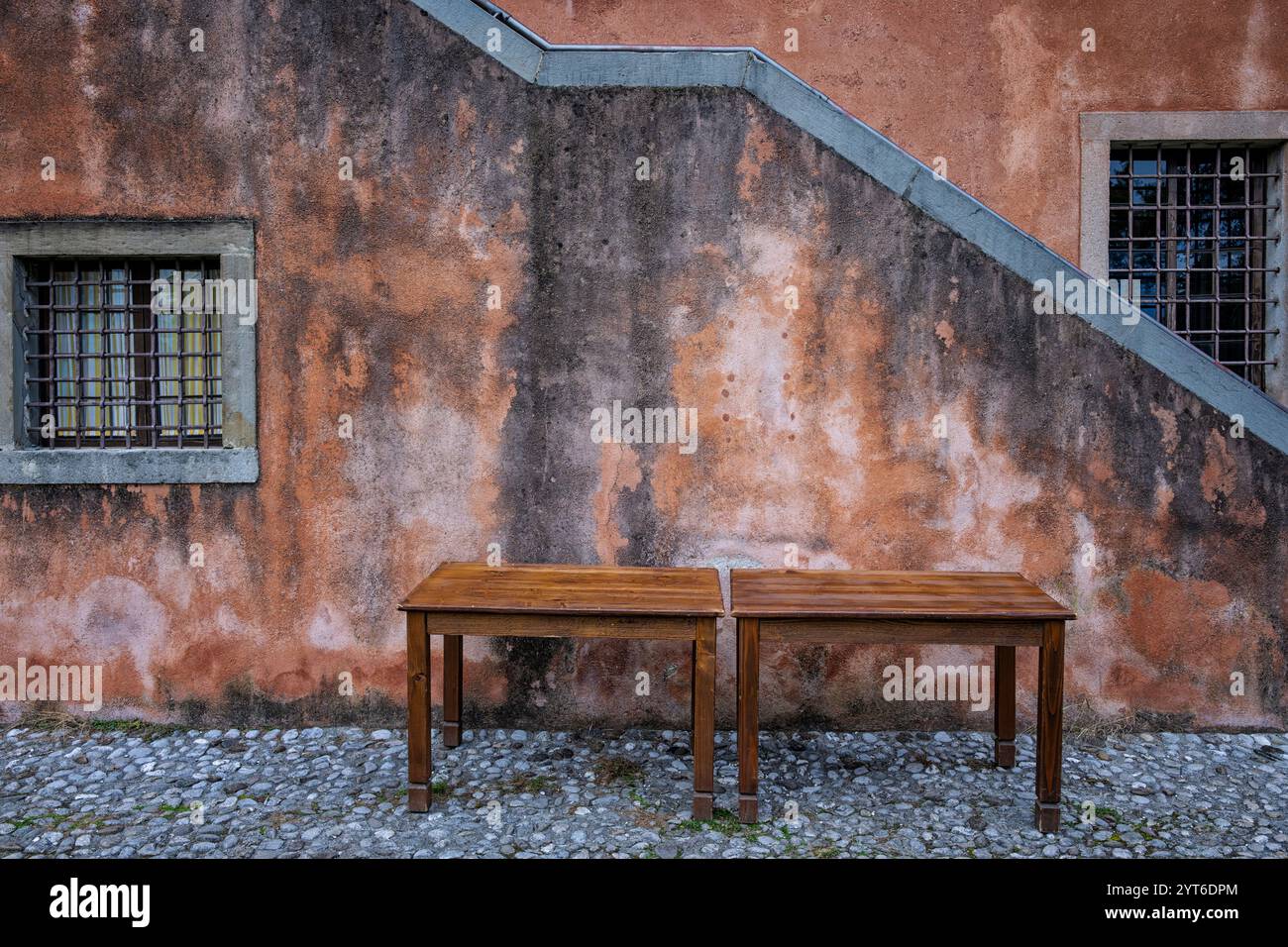 Due tavoli in legno vintage davanti ad una facciata di casa antica. Udine, Friuli Venezia Giulia, Italia. Immagine di composizione minima con spazio di copia. Foto Stock