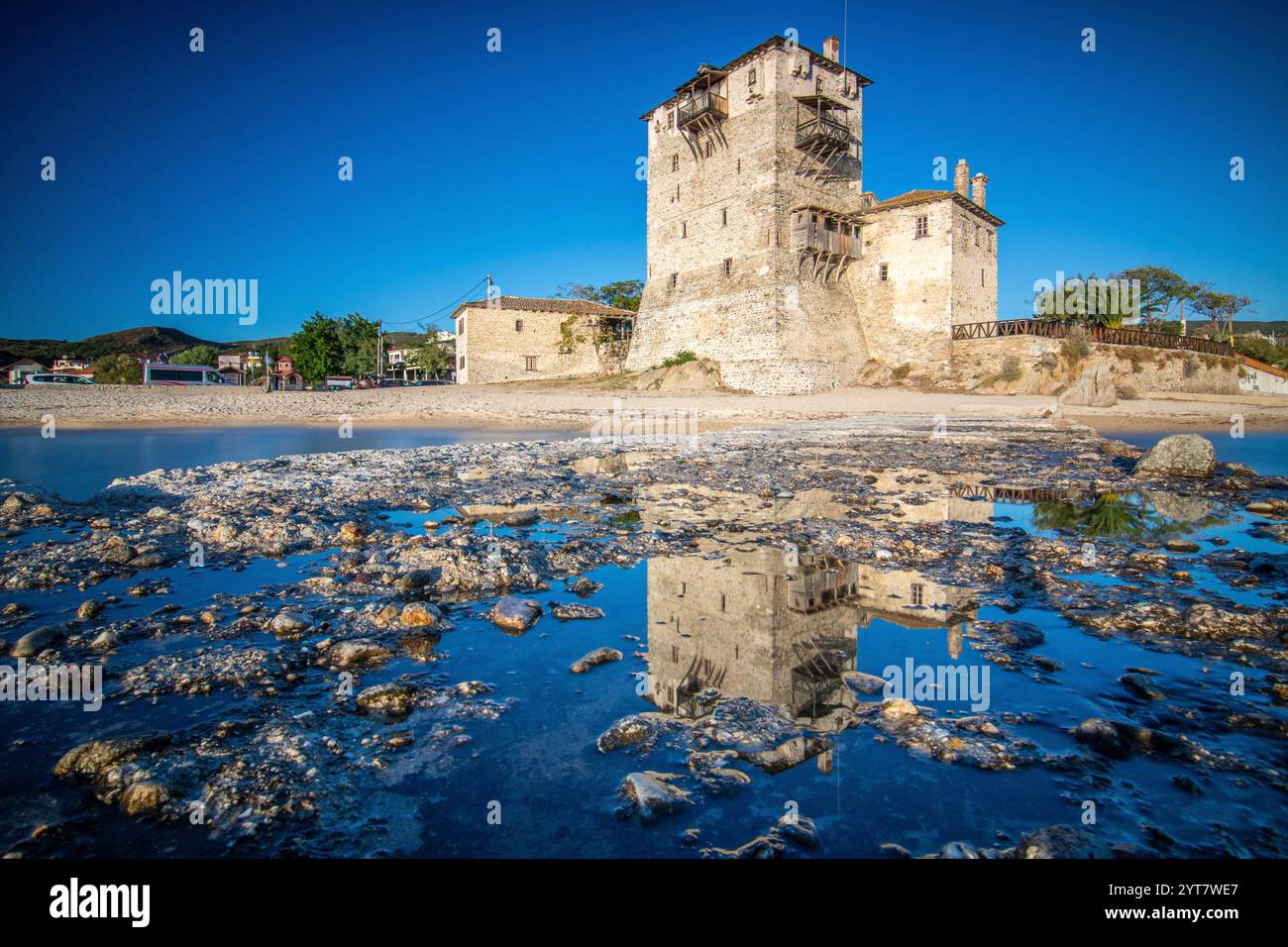 Vista su un molo fino al tramonto. Paesaggio fotografato con il monumento storico della torre bizantina di Prosphorion sulla costa di Ouranoupoli, Salonicco, Macedonia centrale, Grecia Foto Stock
