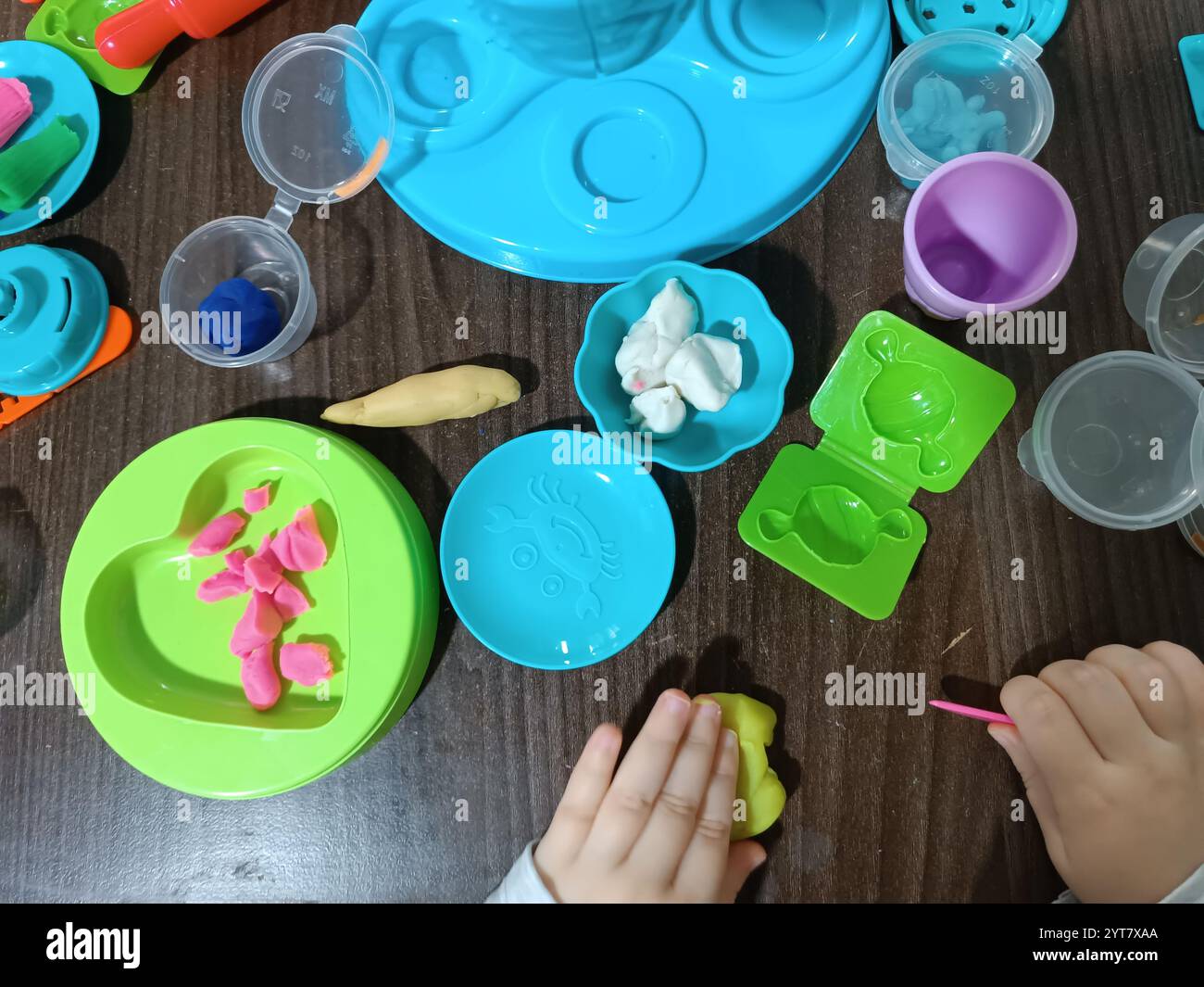 Il bambino modella la plastica morbida, gioca al tavolo con una serie di stampi e un coltello. Giochi educativi. Foto Stock