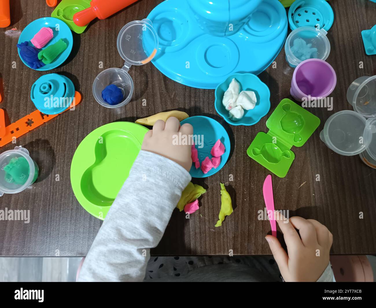 Il bambino modella la plastica morbida, gioca al tavolo con una serie di stampi e un coltello. Giochi educativi. Foto Stock