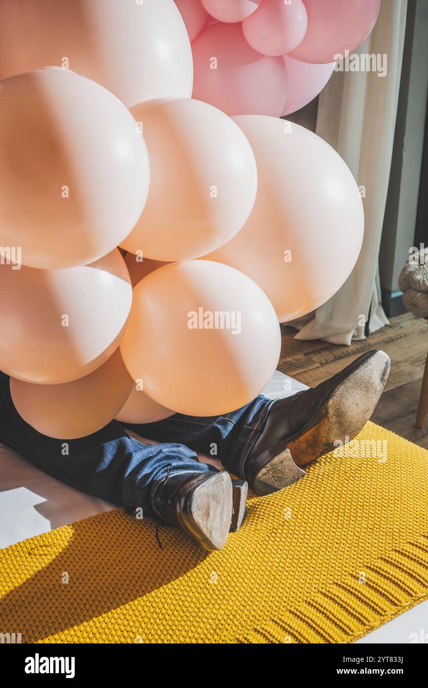 Le gambe inferiori dell'uomo sono coperte da palloncini rosa chiaro Foto Stock
