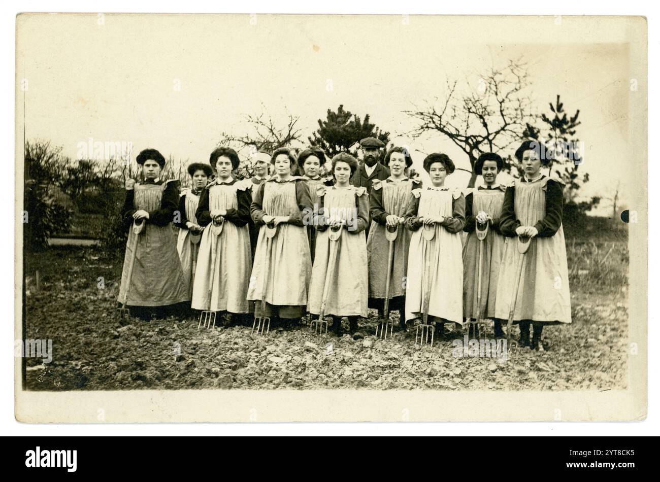 Cartolina edoardiana originale di giovani donne, che tengono forchette, imparano le abilità orticole, forse al college orticolo come Studley, c 1908 -1910 a causa dell'acconciatura. Foto Stock