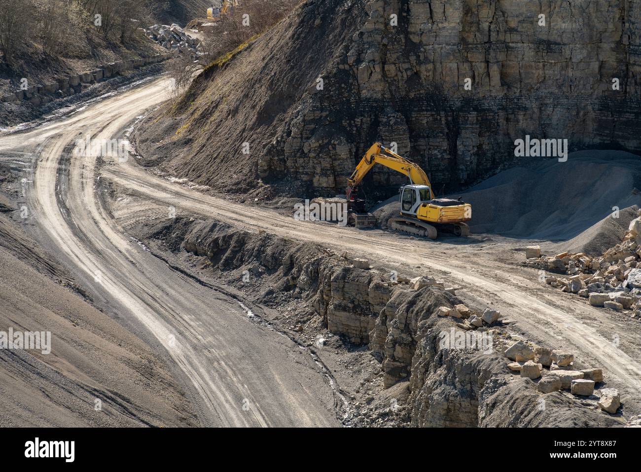 Paesaggio intorno a una miniera a cielo aperto con strade di ghiaia, draga e pareti rocciose in un'atmosfera soleggiata Foto Stock