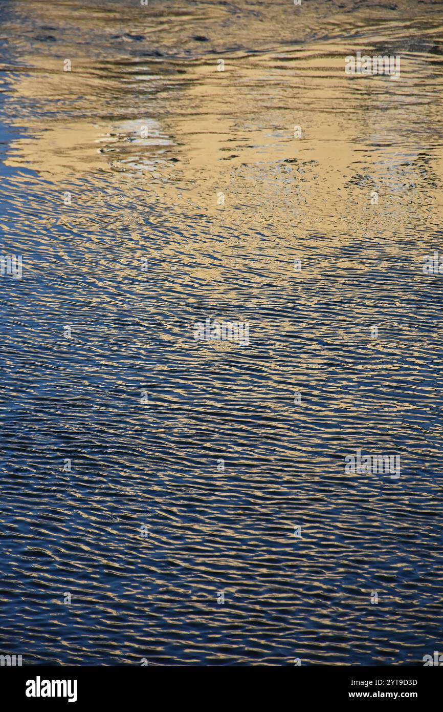 Natura astratta - riflessi dorati nelle acque battute dal vento di un canale Foto Stock