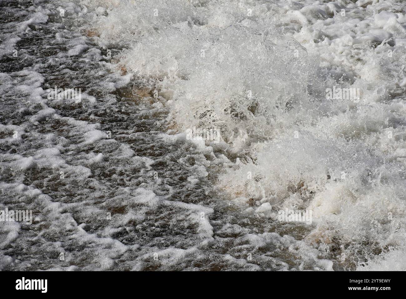 Schiumosità e spruzzi d'acqua su una parete di weir Foto Stock