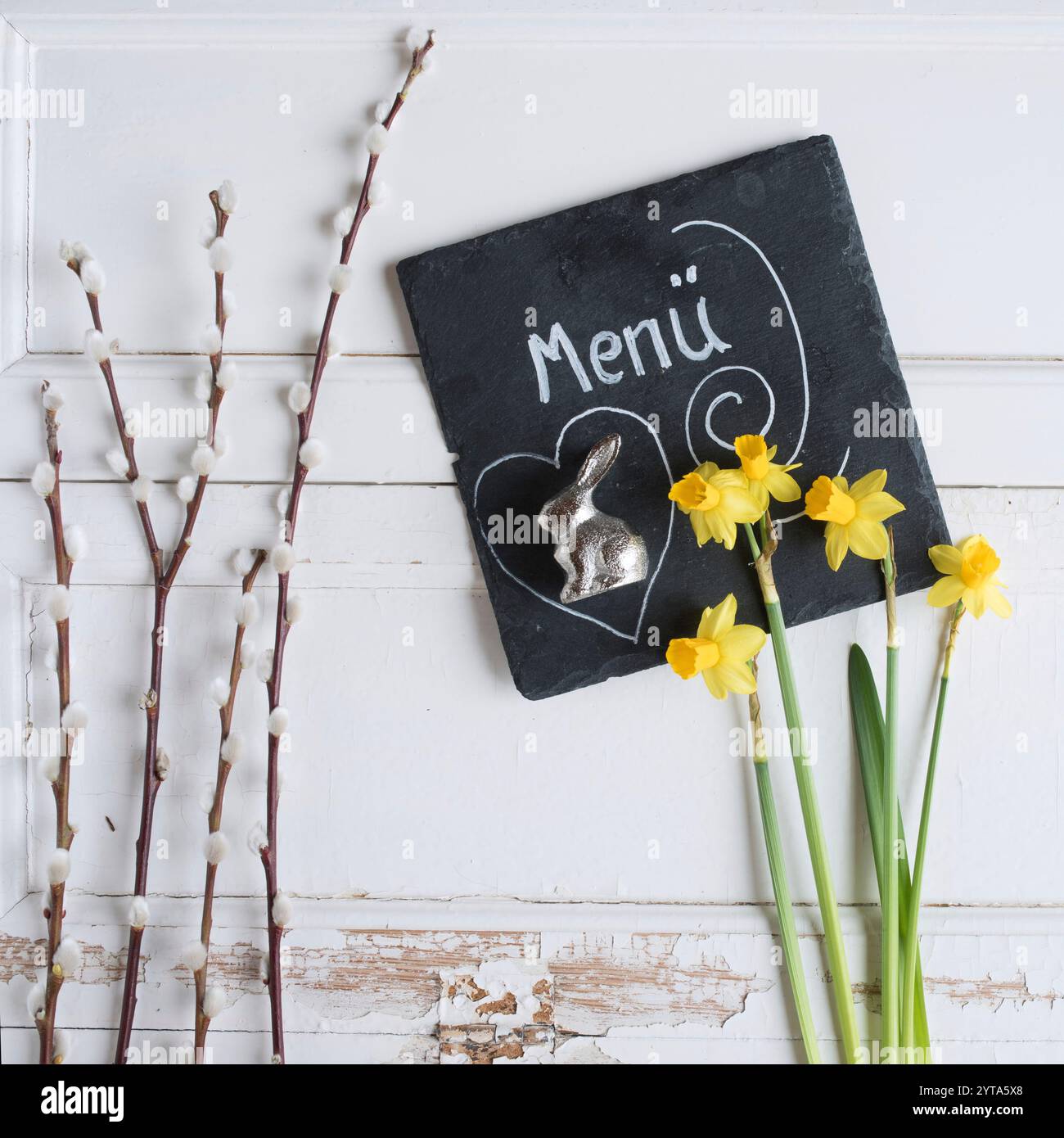 Decorazione con fiori di primavera e piatto di ardesia su legno bianco per un menu di pasqua festivo Foto Stock