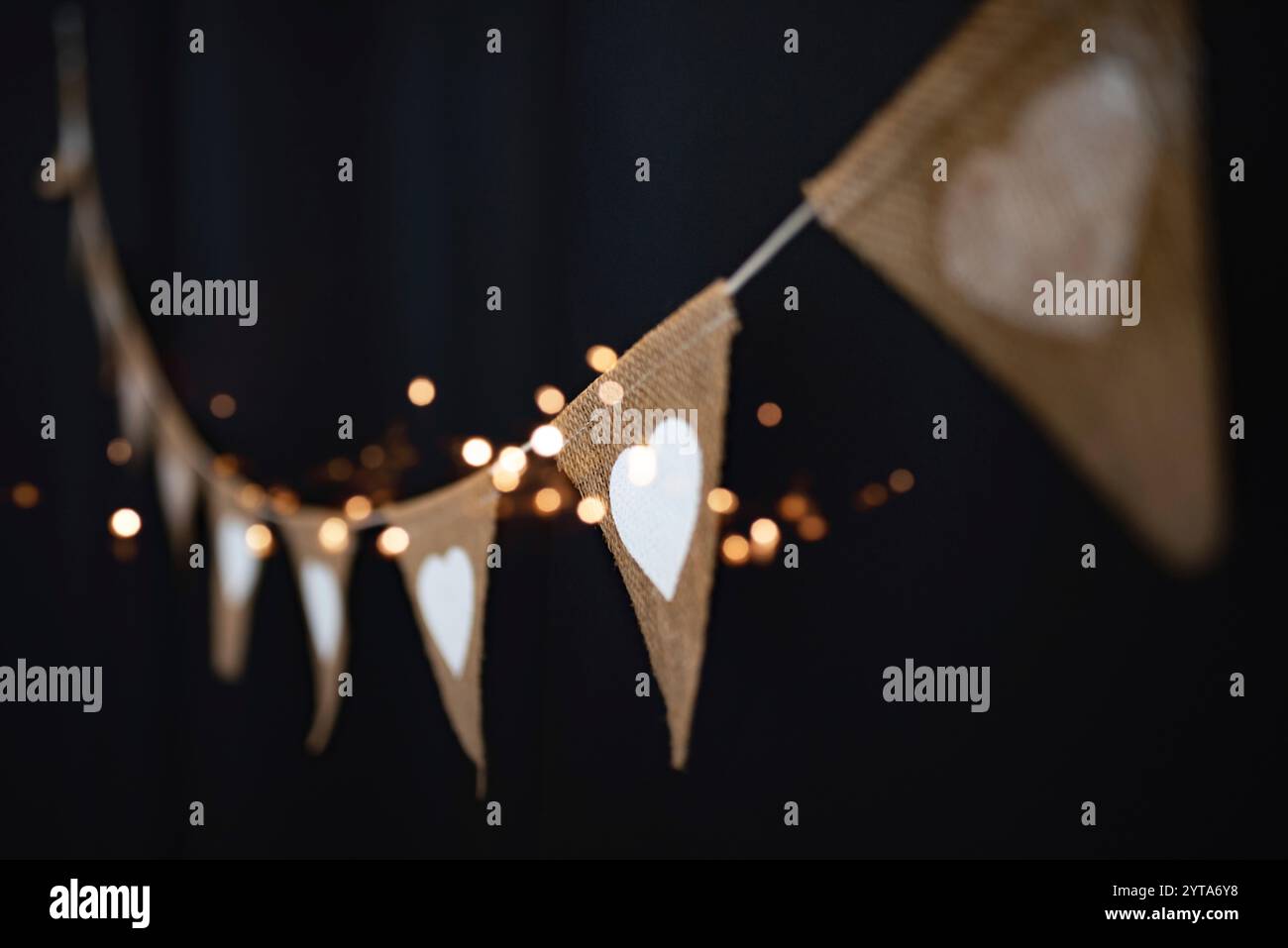 Appeso all'aperto per feste in stile boho con cuori e luci dorate nel cielo notturno. Sfondo per feste estive con breve profondità di campo per matrimoni e vacanze. Foto Stock