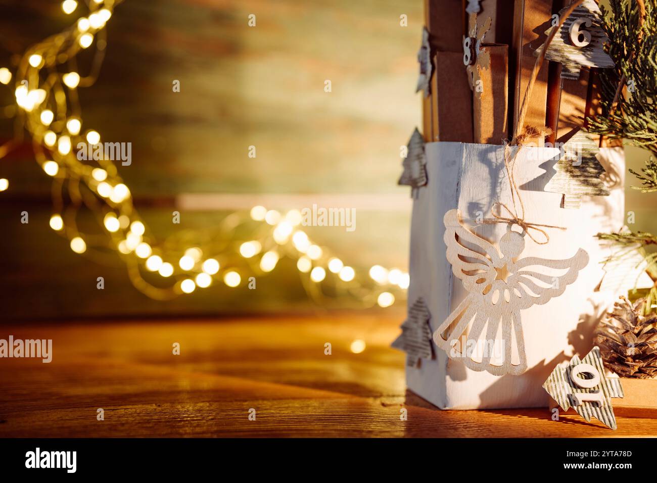 Calendario dell'Avvento con luci natalizie su legno rustico. Confezione natalizia ecologica fatta a mano con luci sfocate. Foto Stock