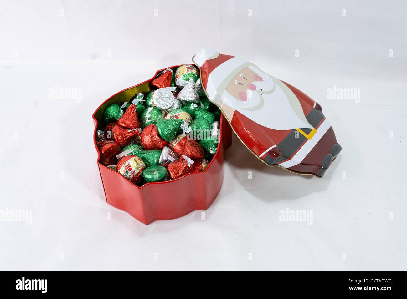 Una latta natalizia a forma di Babbo Natale contiene caramelle al cioccolato avvolte. La parte superiore è stata rimossa, mostrando una scatola piena di caramelle. Foto Stock