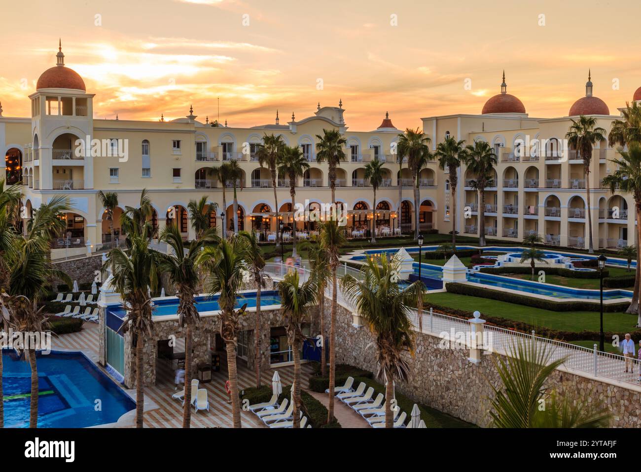 Un hotel con una piscina e un muro di palme. L'hotel si trova in un paese straniero Foto Stock