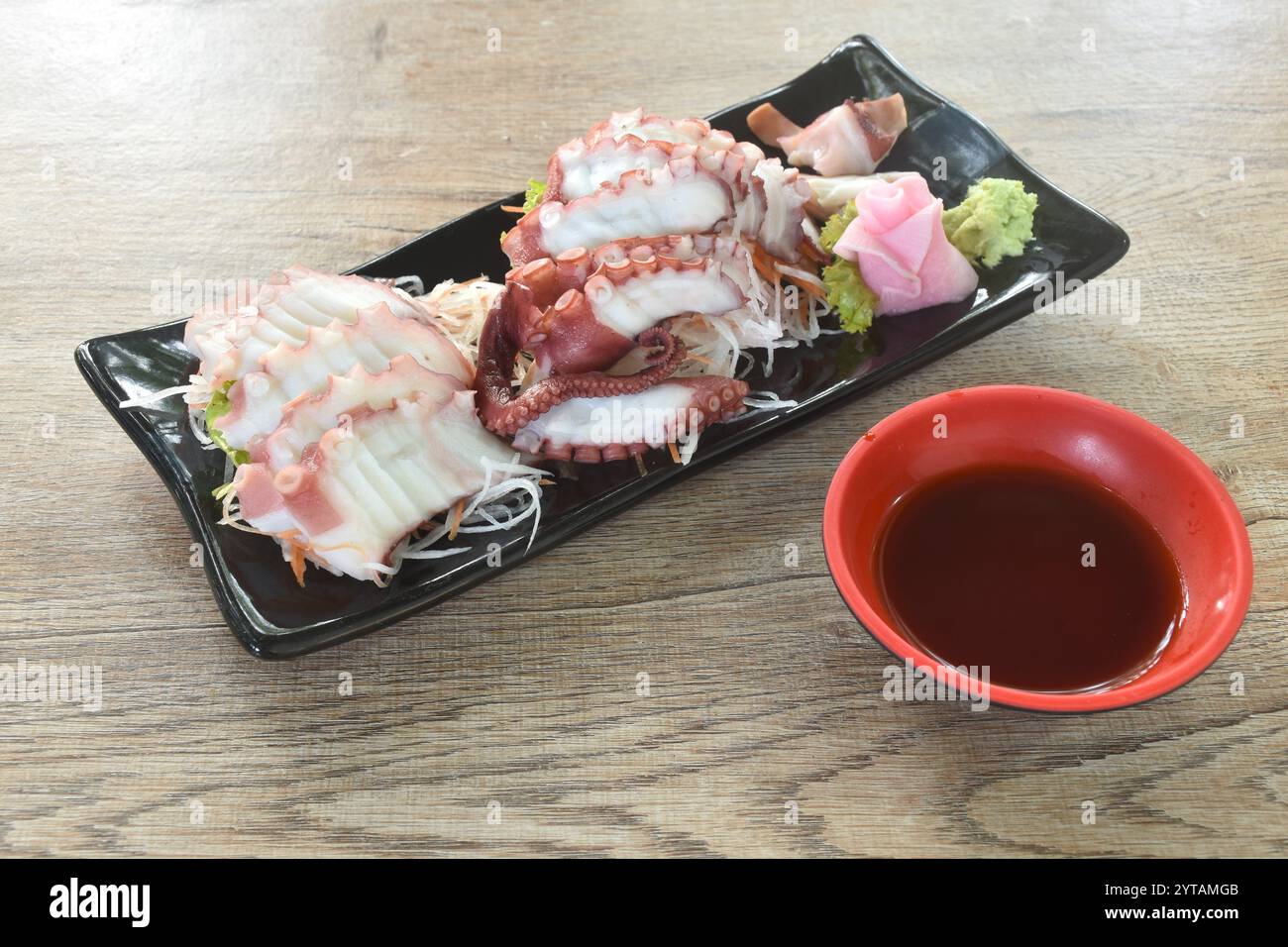 Tako Sushi o affettare il tentacolo di polpo con salsa di soia wasabi. Mangiare il ravanello di coppia e lo zenzero rosa sottaceto sul piatto Foto Stock