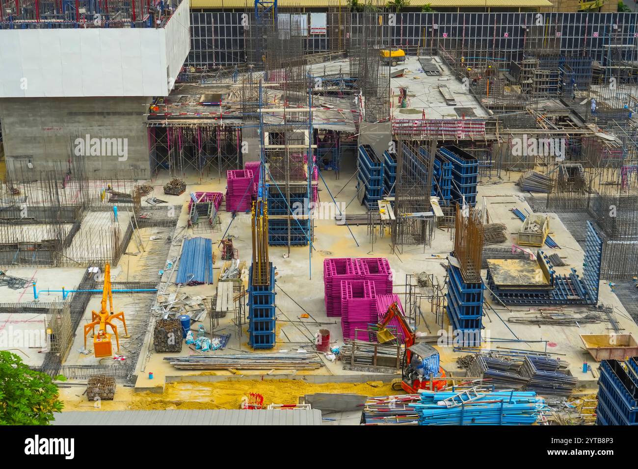 Costruzione del primo piano, fondazioni in cemento, supporti del futuro grattacielo, installazione di una gru da costruzione e versamento di cemento liquido. Foto Stock