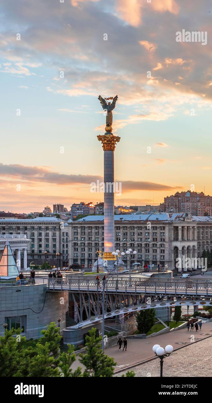 Questa foto mostra Kiev al tramonto, con il Monumento all'indipendenza di Maidan Nezalezhnosti, con sfumature dorate, edifici storici e un vivace urba Foto Stock