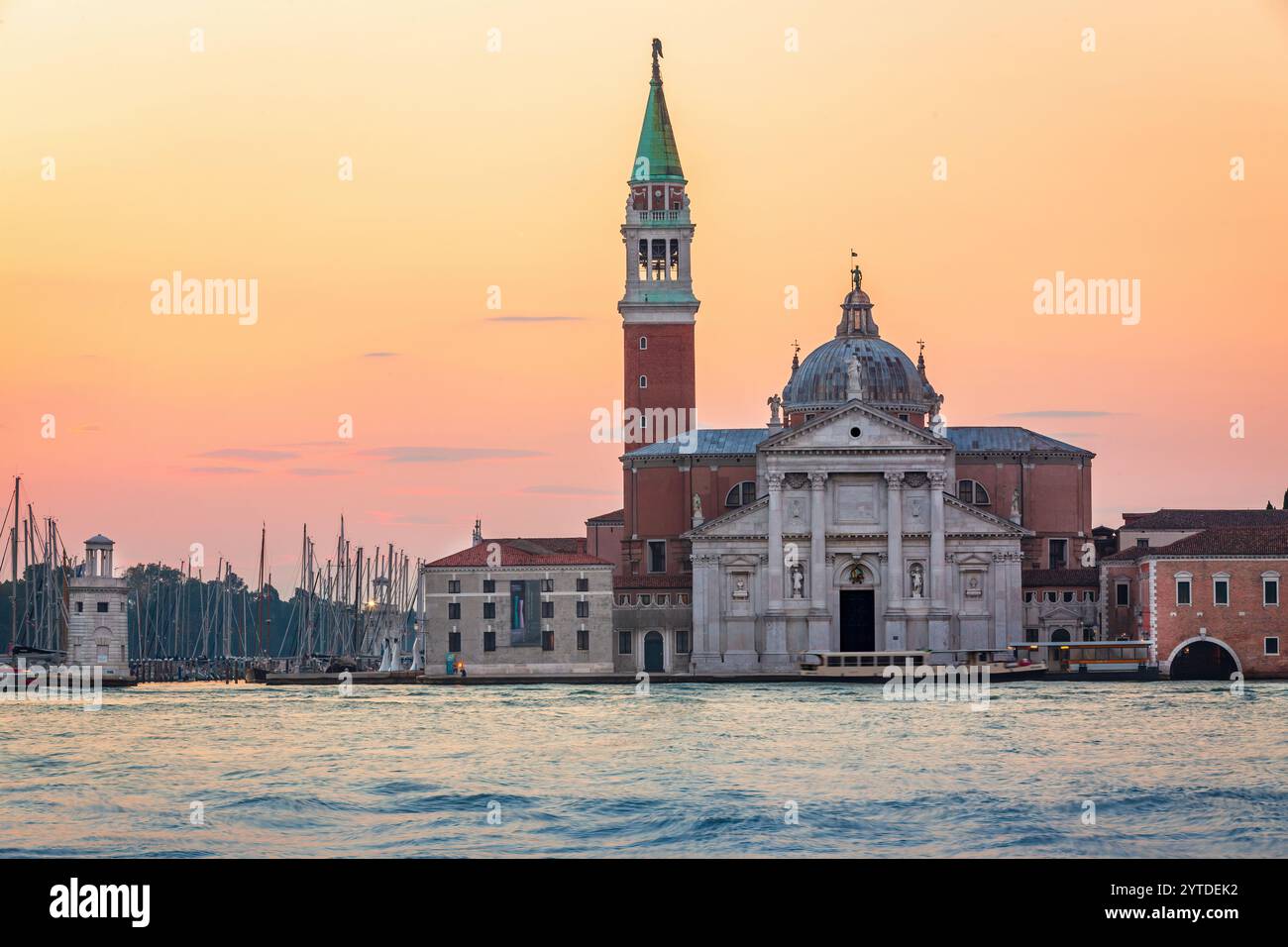 Questa foto cattura Venezia all'alba, con l'iconica chiesa di San Giorgio maggiore e il suo campanile, con acque calme e un morbido rif Foto Stock