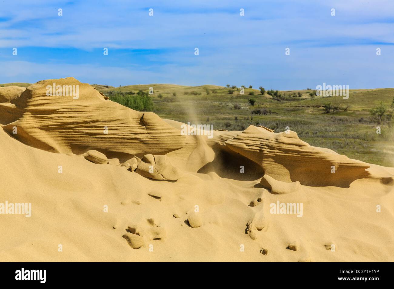 Un vasto deserto sabbioso con una grande formazione rocciosa al centro. Il cielo è limpido e nuvoloso, creando un'atmosfera serena e tranquilla. Le rocce A. Foto Stock