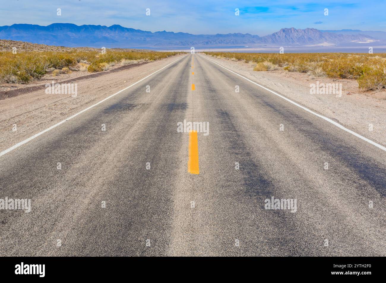 Una strada lunga e vuota con linee gialle. La strada è vuota e il cielo è limpido. La strada è lunga e rettilinea, senza auto o persone in vista Foto Stock