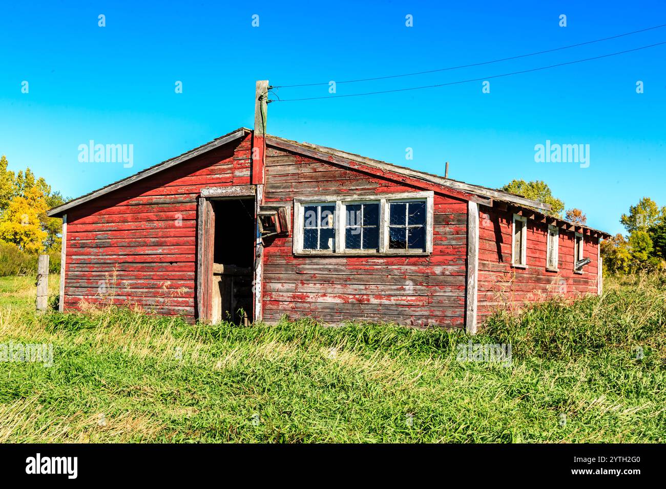 Un fienile rosso con un camino e una finestra. Il fienile è vecchio e ha un aspetto rustico Foto Stock