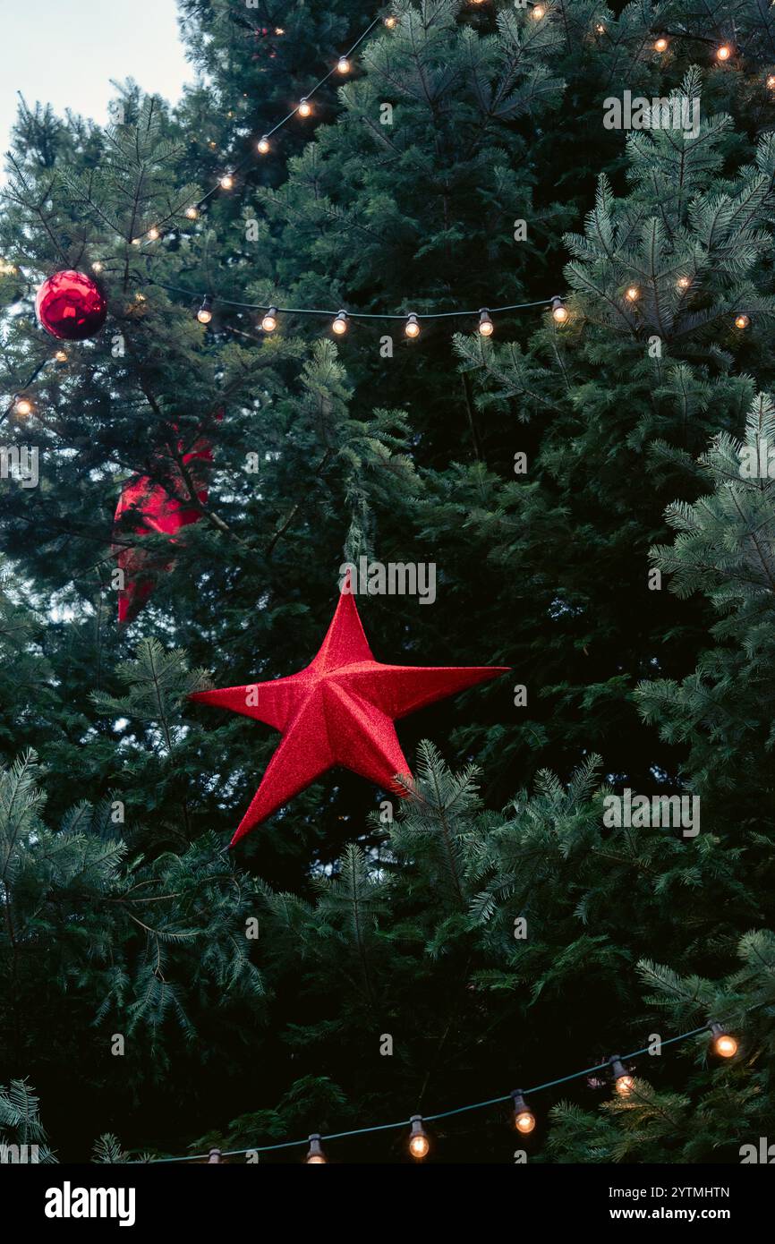 Un albero di Natale splendidamente decorato con ornamenti rossi e luci festive. Foto di alta qualità Foto Stock