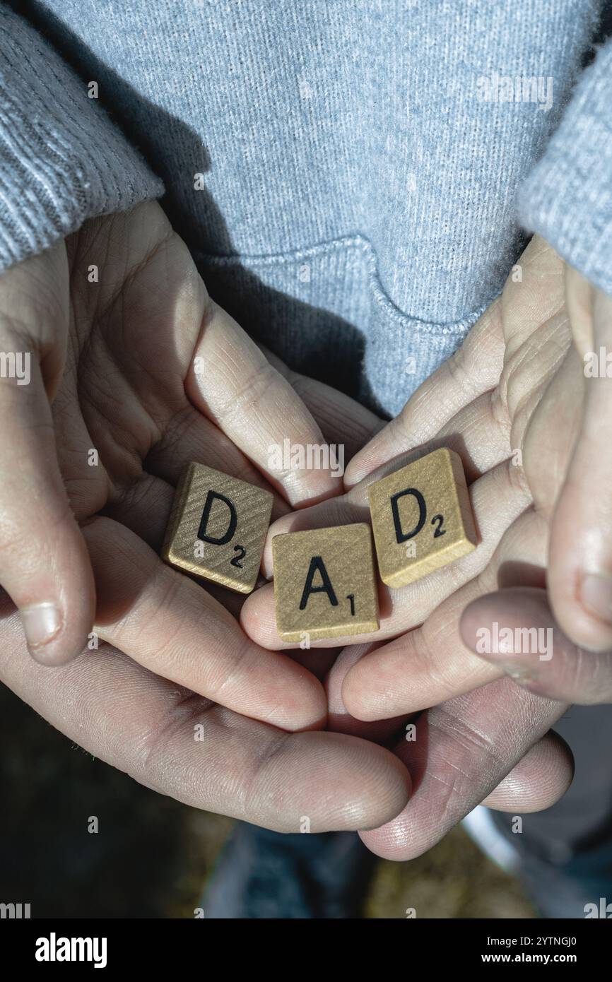 Bambino e padre si uniscono con la parola "PAPÀ" su piastrelle strapazzabili Foto Stock