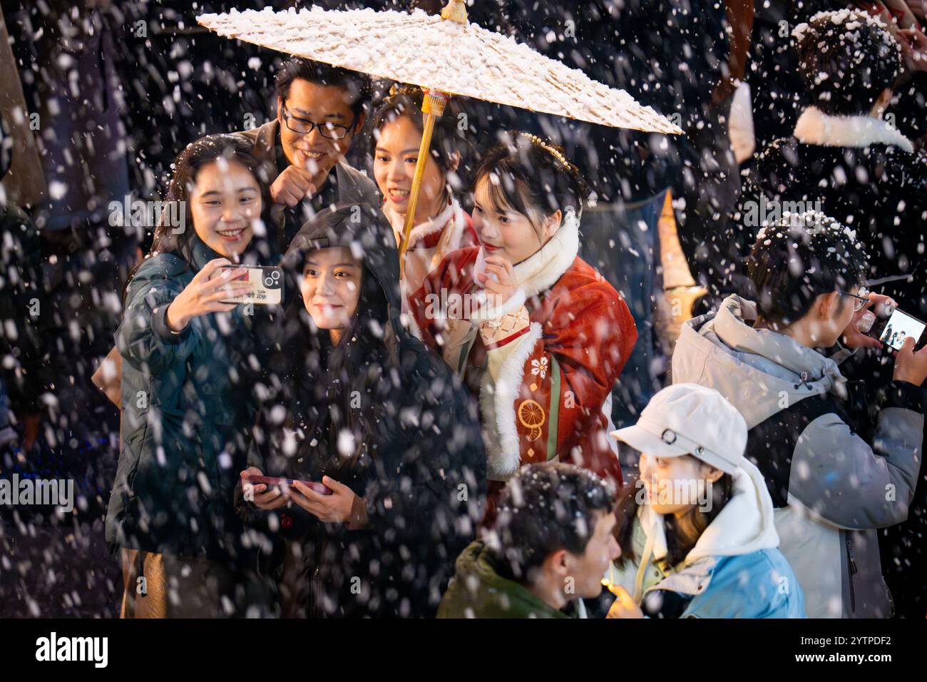 Le persone scattano foto di fiocchi di neve artificiali al Chongqing Changjiahui Shopping Park di Chongqing, Cina, 7 dicembre 2024. Foto Stock