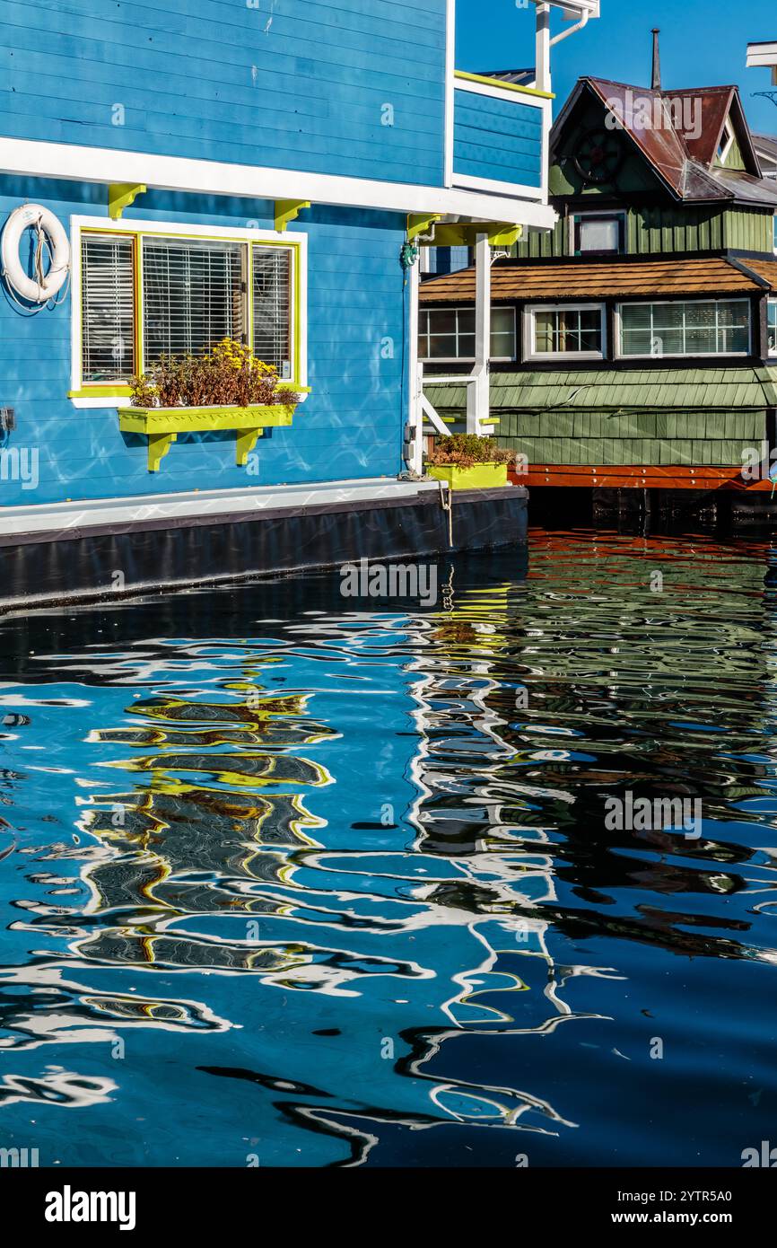 Una casa blu con un rivestimento giallo si trova accanto a un corpo d'acqua. L'acqua è calma e riflette la casa blu e l'area circostante Foto Stock Una casa blu con un rivestimento giallo si trova accanto a un corpo d'acqua. L'acqua è calma e riflette la casa blu e l'area circostante Foto Stock