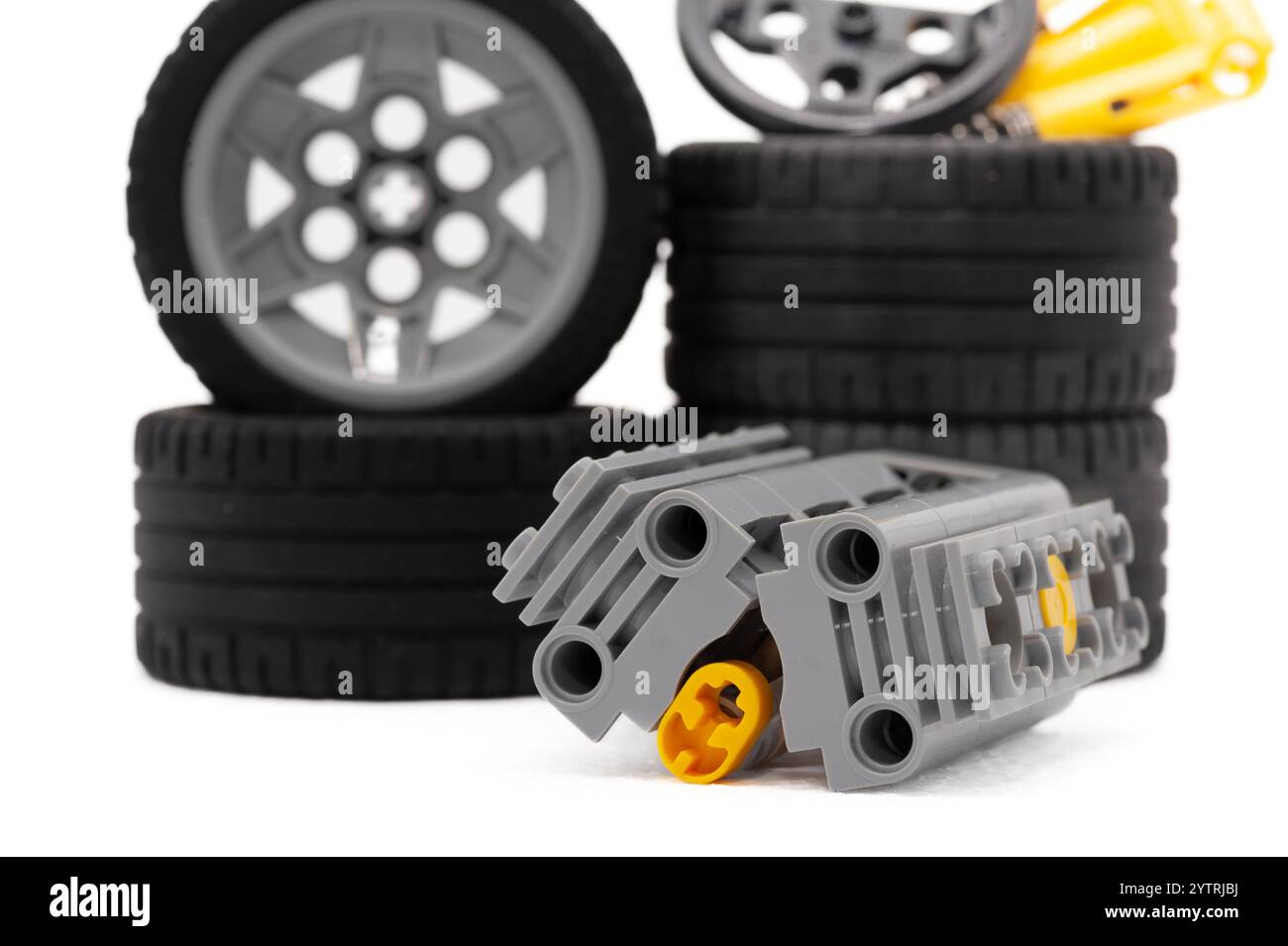 Un motore giocattolo grigio con cerchi gialli. Il motore si trova su una superficie bianca. Sullo sfondo sono presenti quattro ruote. LEGO. Polonia, Varsavia 06.12.2024 Foto Stock