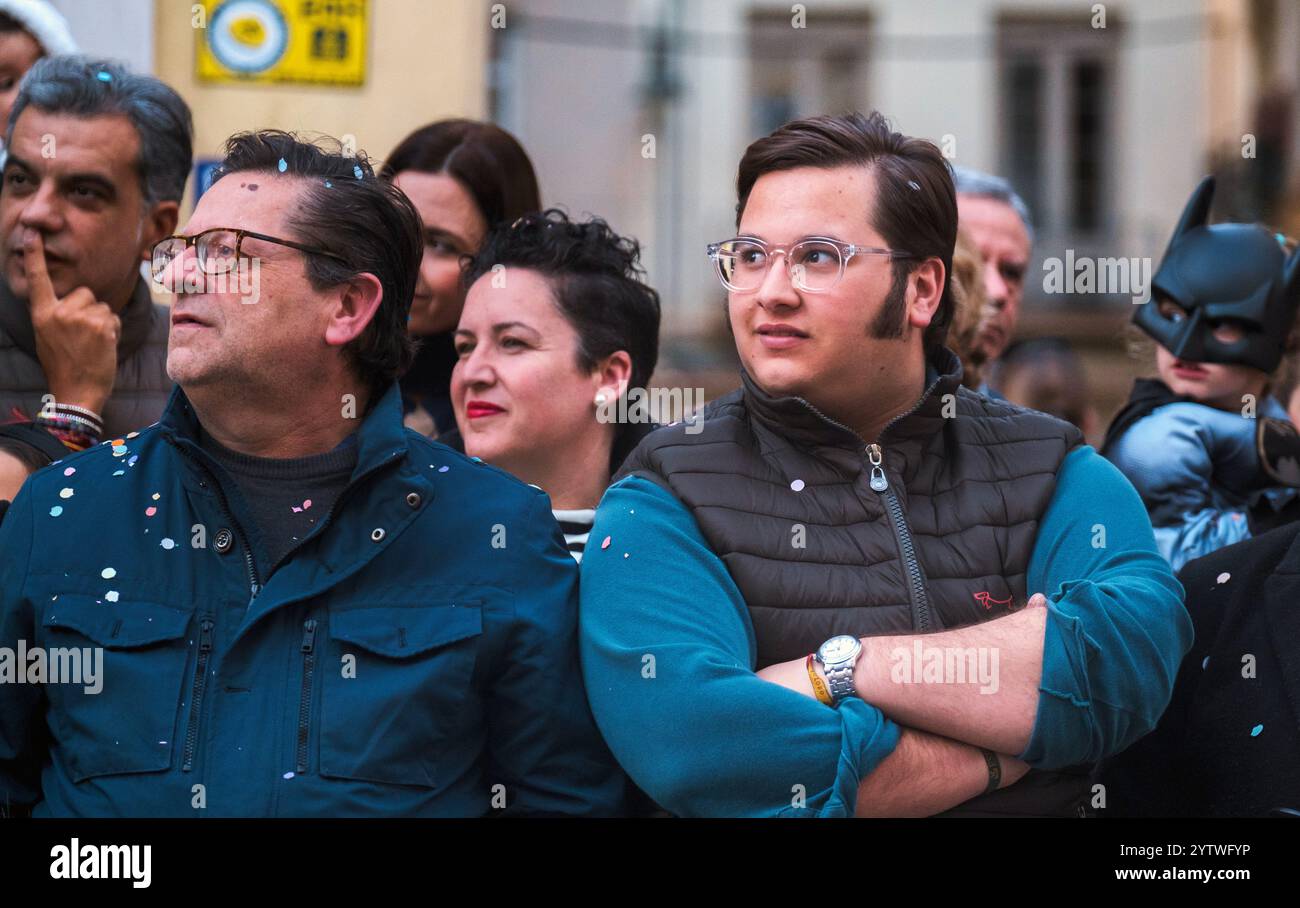 L'immagine mostra un gruppo di persone che guardano qualcosa con interesse. Sulla destra c'e' una persona vestita con un costume di Batman, che suggerisce che il Foto Stock