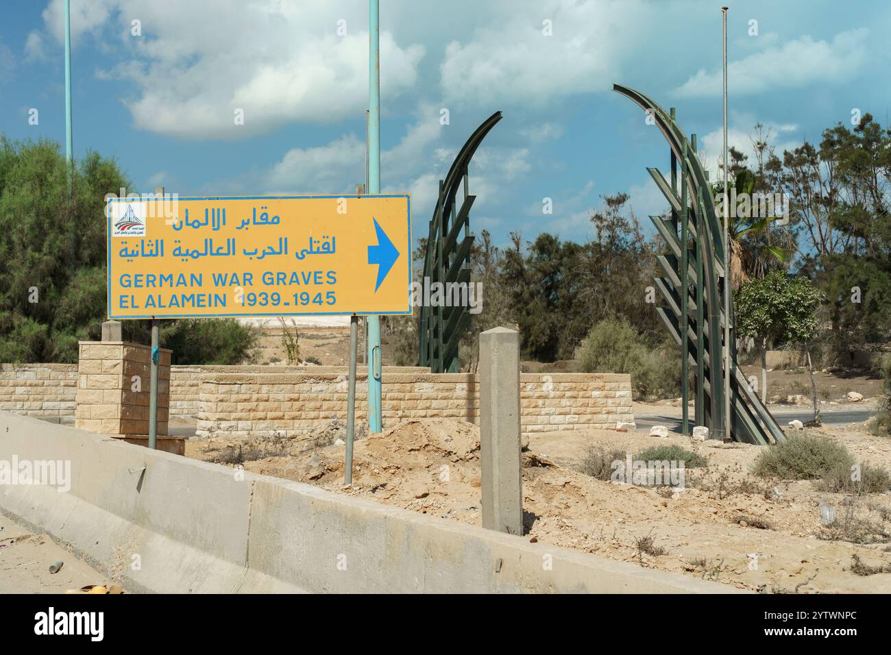 Un cartello direzionale a El Alamein indica il cimitero di guerra tedesco, commemorando i soldati tedeschi sepolti lì durante la prima e la seconda guerra mondiale Foto Stock