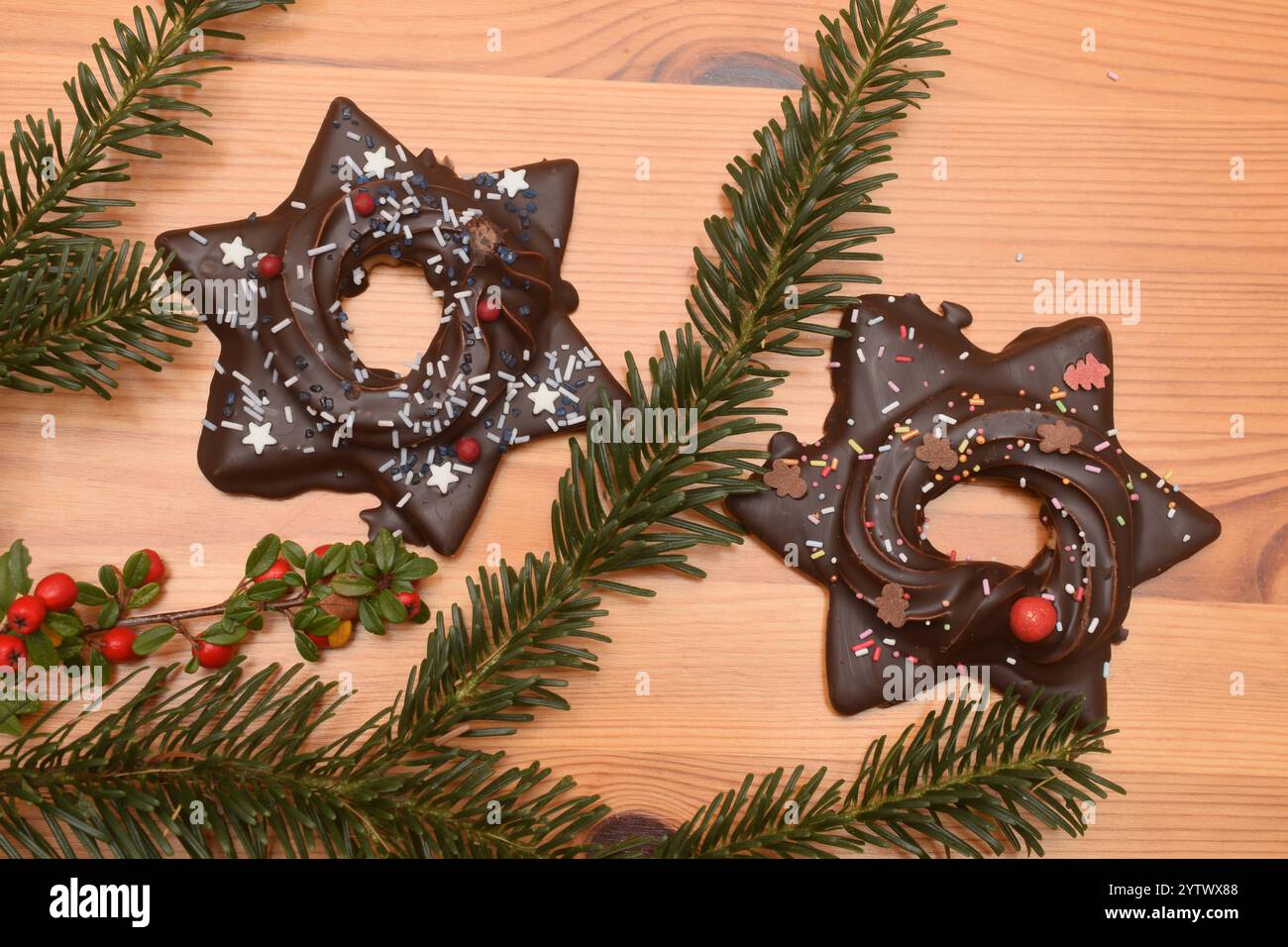 06.12.2024 Lebkuchen Deutschland/ Sachsen Anhalt/ Altmark/ Altmarkkreis Salzwedel/ Stadt Klötze/ Kusey/ Lebkuchen/ Weihnachtsgebäck/ Gebäck/ zwei Lebkuchensterne mit Cremefüllung und Schokoladenüberzug liegen auf einem Holztisch/ Tannenzweig und Vogelbeeren als Dekoration *** 06 12 2024 Gingerbread Klötze Foto Stock