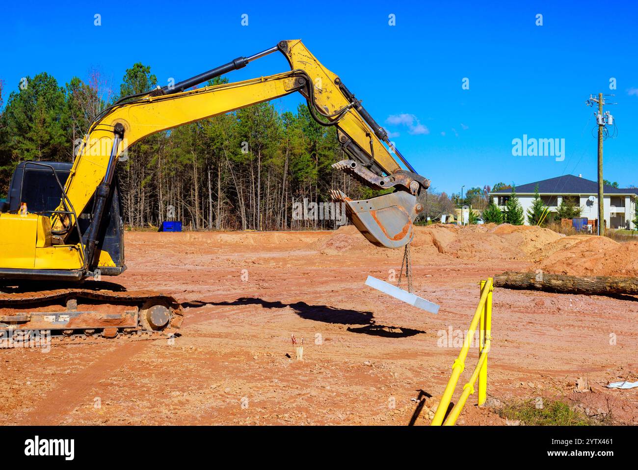 Un escavatore utilizza il suo braccio per sollevare lastre di calcestruzzo nel cantiere durante l'area residenziale dei lavori di costruzione Foto Stock