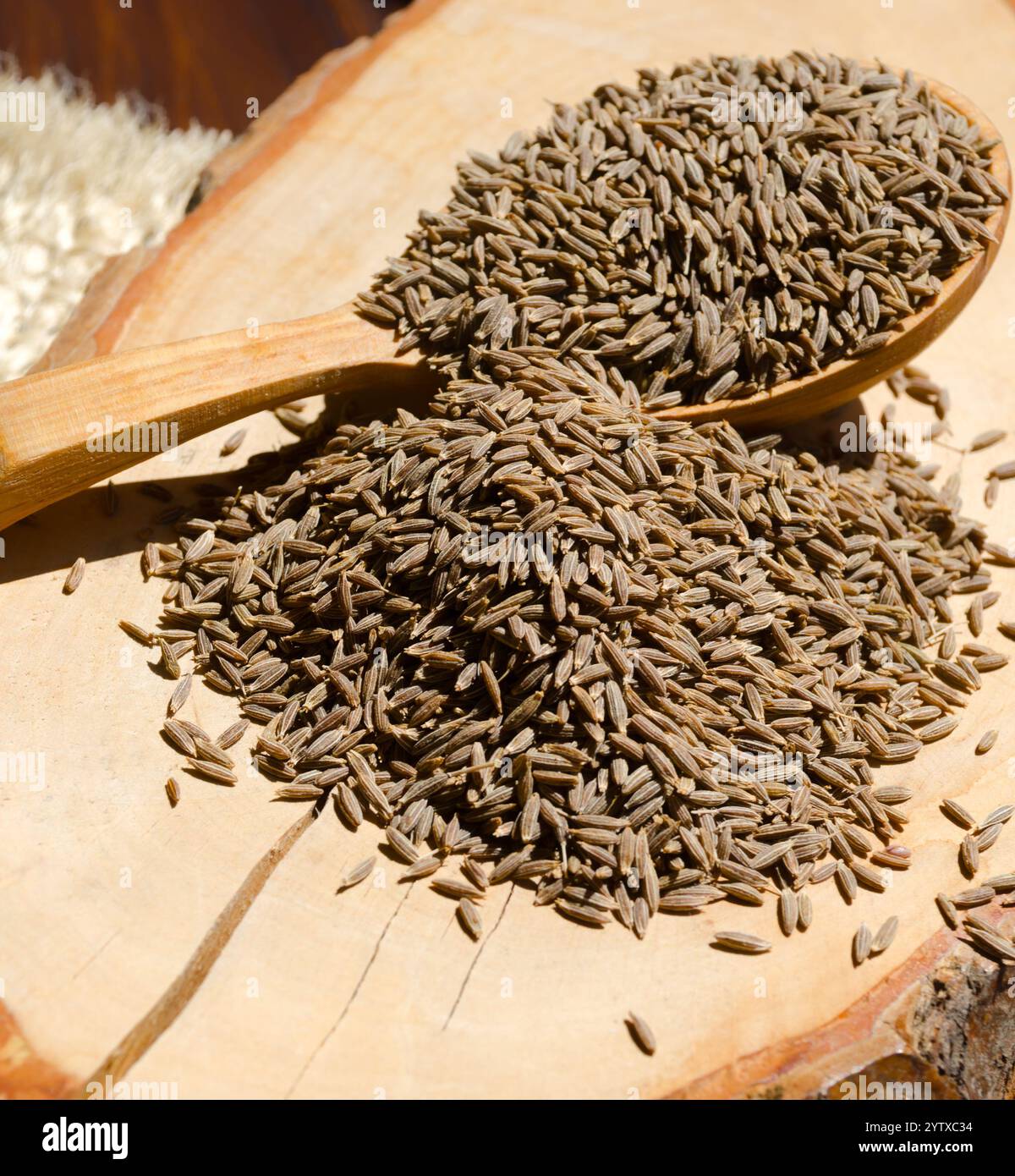 Spezie orientali zira. Cumino su un cucchiaio su un asse di legno. Foto Stock