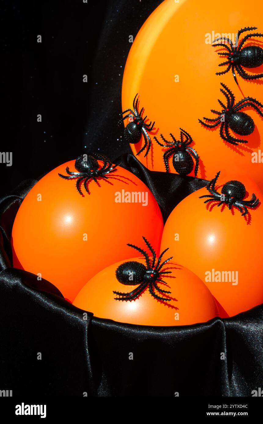 Arredamento di Halloween - un sacco di ragni neri su una luce notturna arancione. Su uno sfondo nero, inserire il testo. Foto Stock