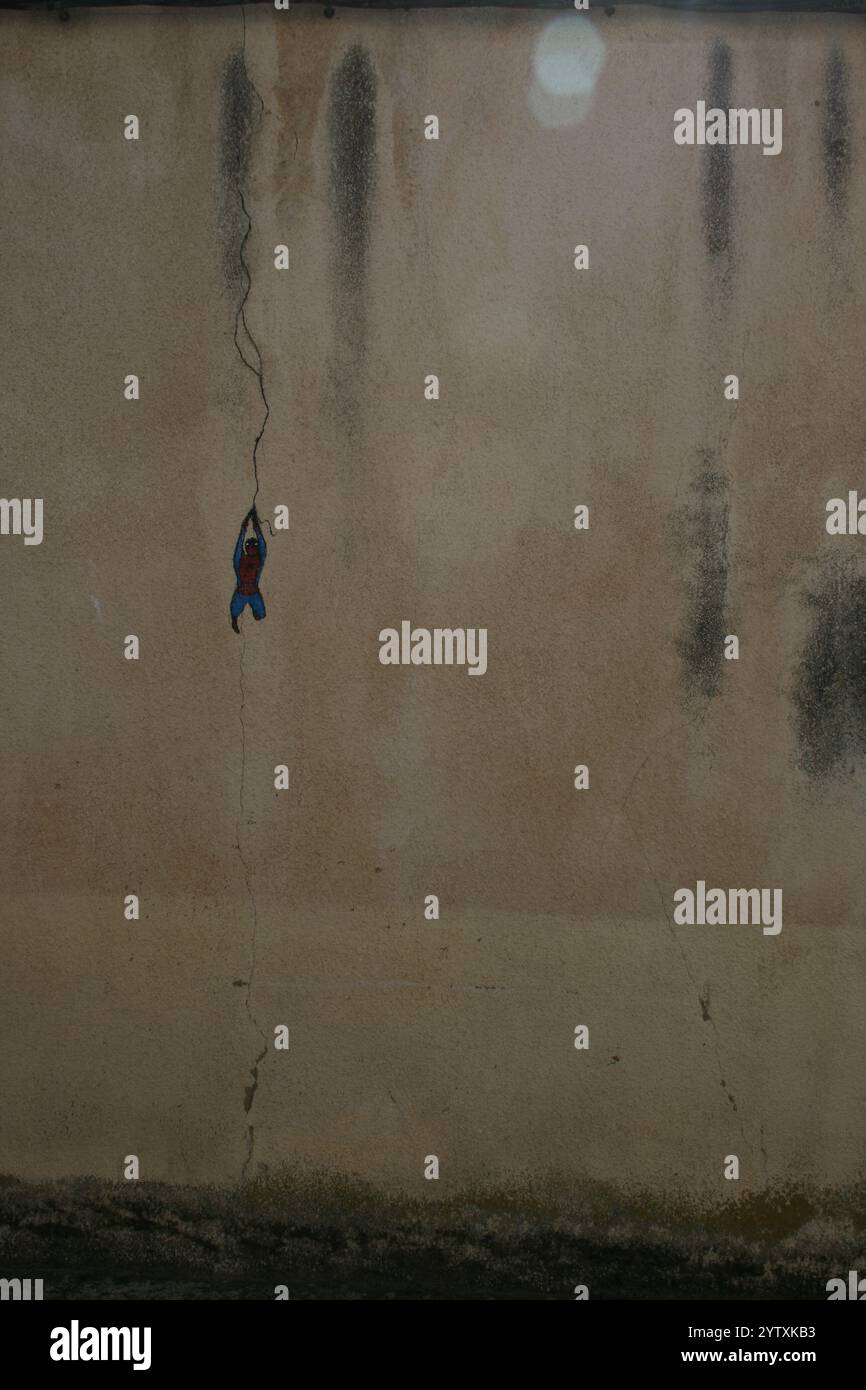 Grafitti Spiderman appeso a una crepa nel muro Foto Stock