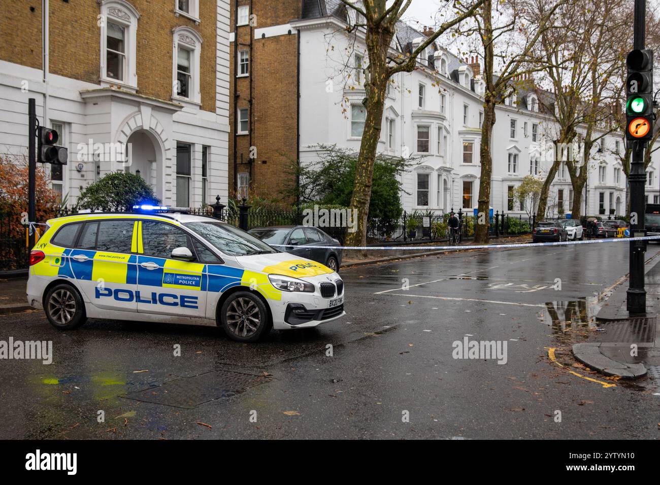 Londra, Regno Unito. 8 dicembre 2024. Una macchina della polizia blocca la strada davanti a un nastro bianco e blu. I chirurghi rimuovono un albero che è caduto dall'altra parte della strada e in un edificio. Durante la tempesta Darragh nelle prime ore di una domenica mattina, forti venti e forti piogge hanno causato l'allentamento dell'albero di London Plain e la caduta dall'altra parte della strada danneggiando l'edificio di fronte. Credito: SOPA Images Limited/Alamy Live News Foto Stock
