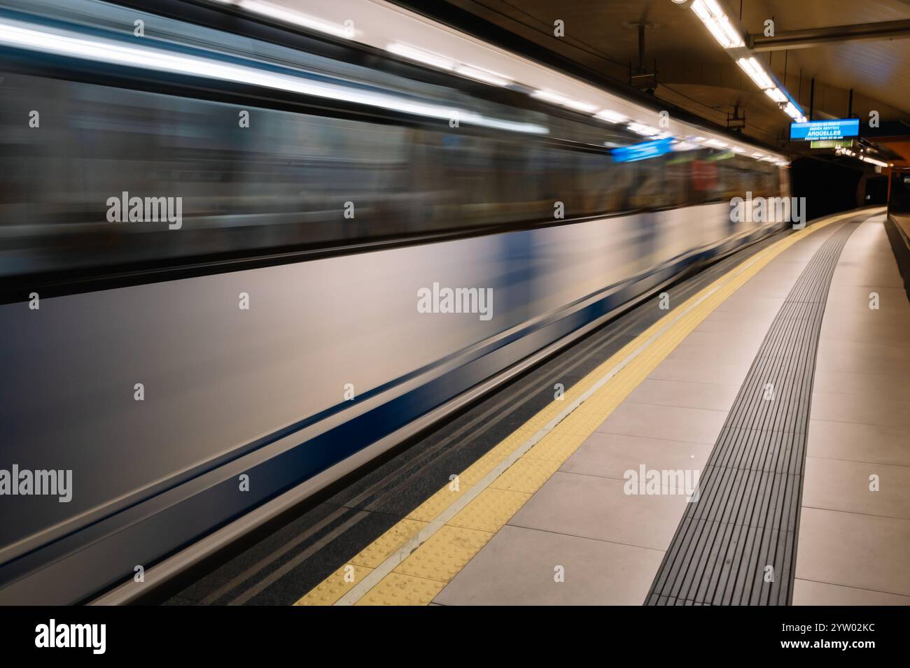 Immagine sfocata di un treno su una piattaforma della metropolitana con un bambino che cammina sulla piattaforma. Il treno si sta muovendo rapidamente, e il bambino sta camminando verso di esso. Foto Stock